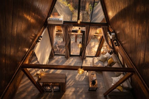 Вечерний интерьер A-frame домика «Грань» с панорамными окнами и теплым светом.